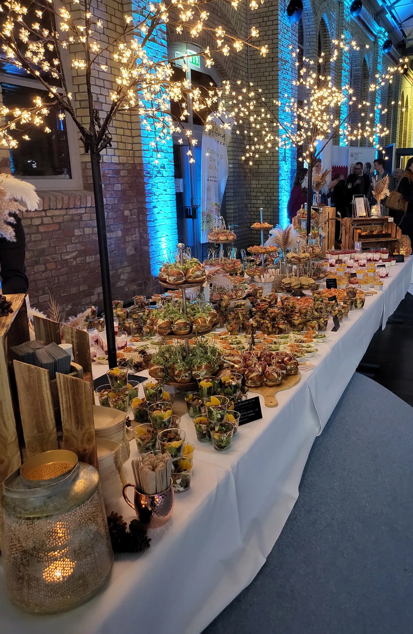 Lange Buffettafel mit Fingerfood und Desserts unter Lichterbäumen bei einer Firmenveranstaltung