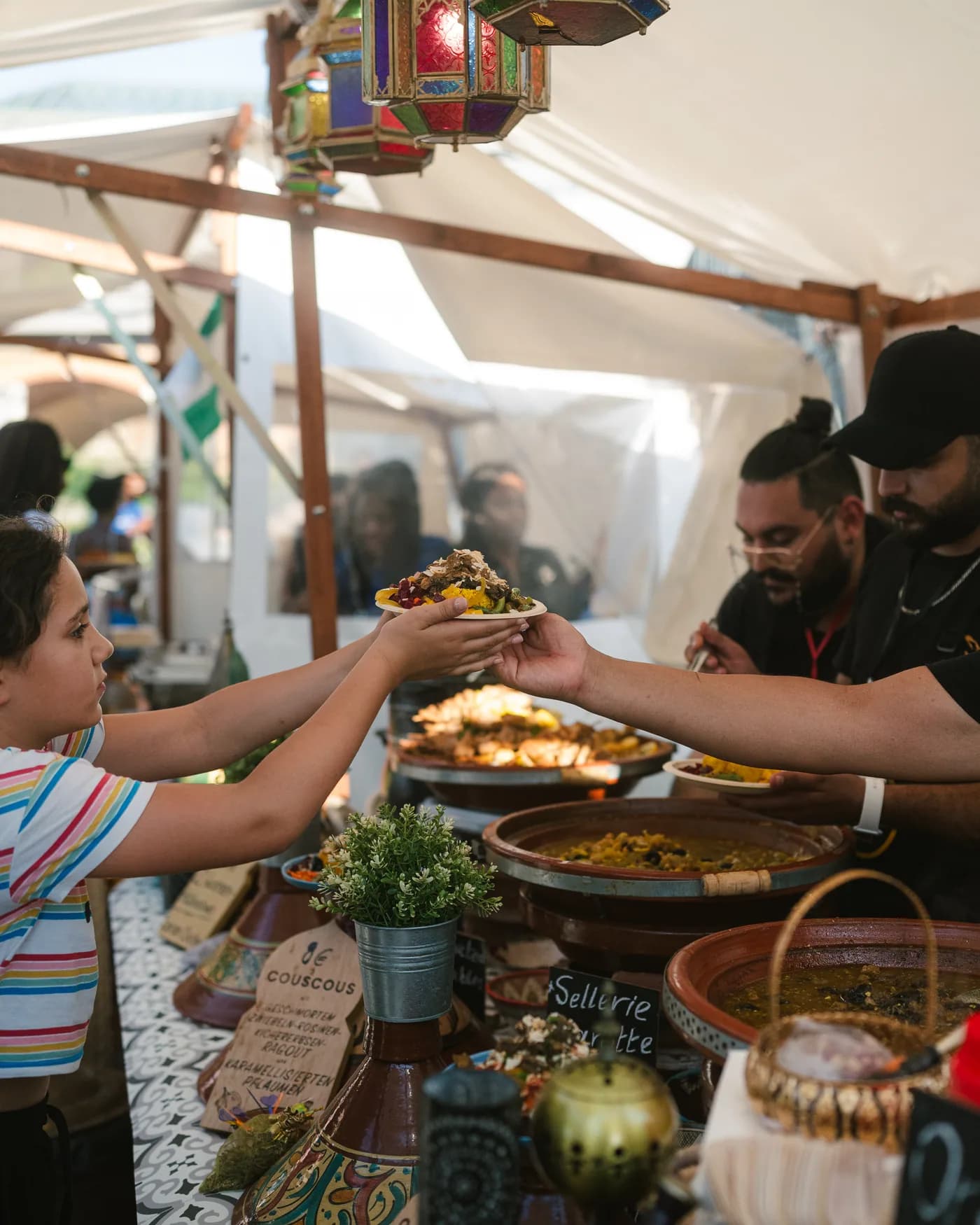 Ein Kind nimmt einen Teller Couscous am Stand entgegen