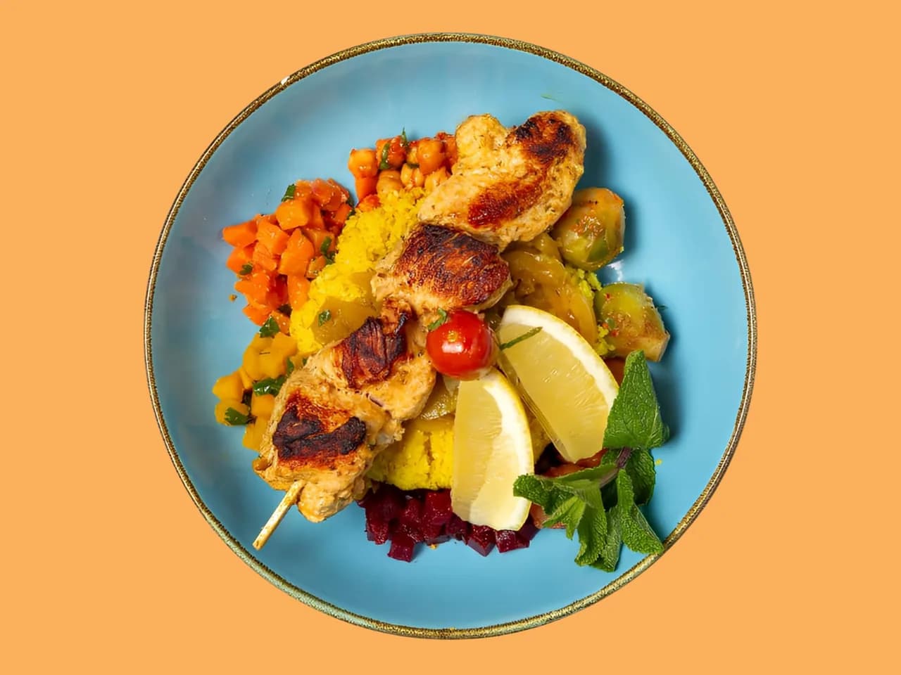 Couscous Marrakesh von oben: gegrillte Hähnchenspieße mit Zitrone auf einem blauen Teller